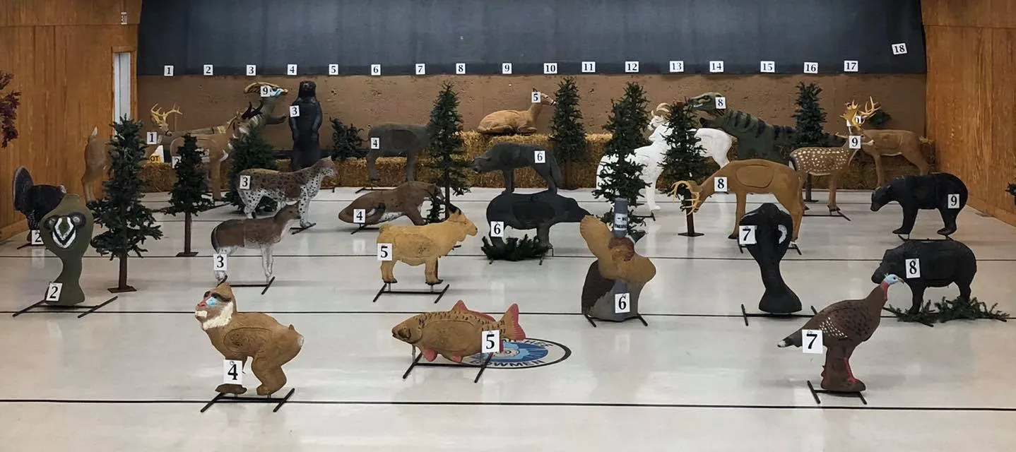 An indoor archery range with a wide array of 3D archery targets set at a range of distances