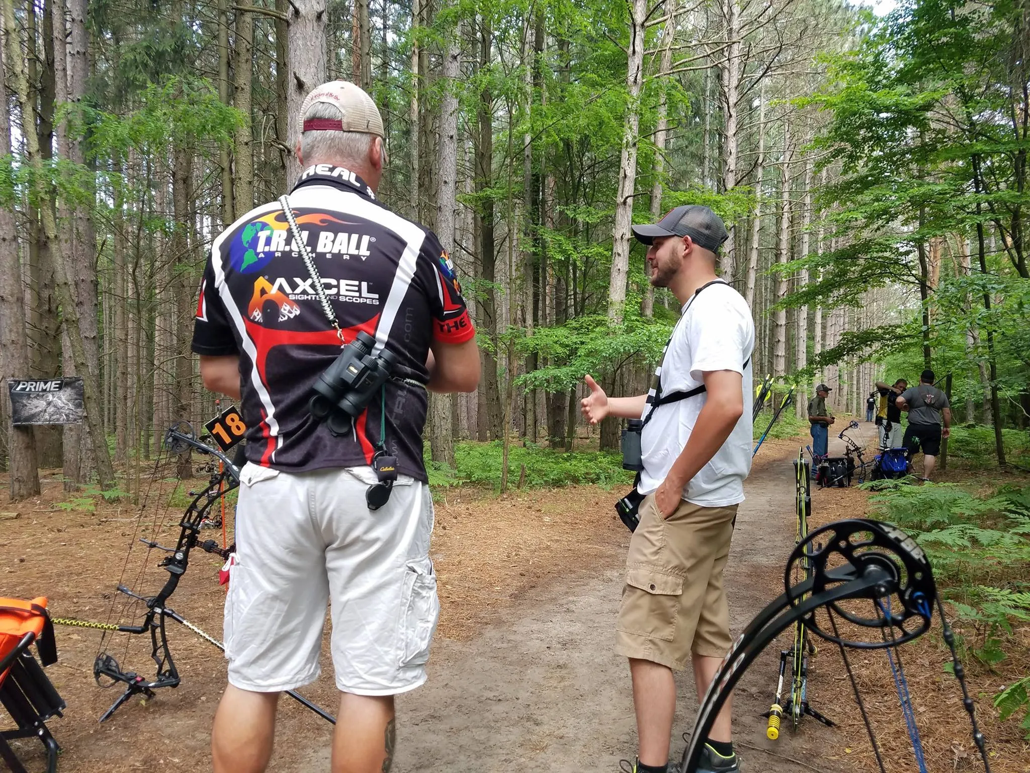 Adult archers on an outdoor course in the woods stopping to have a conversation